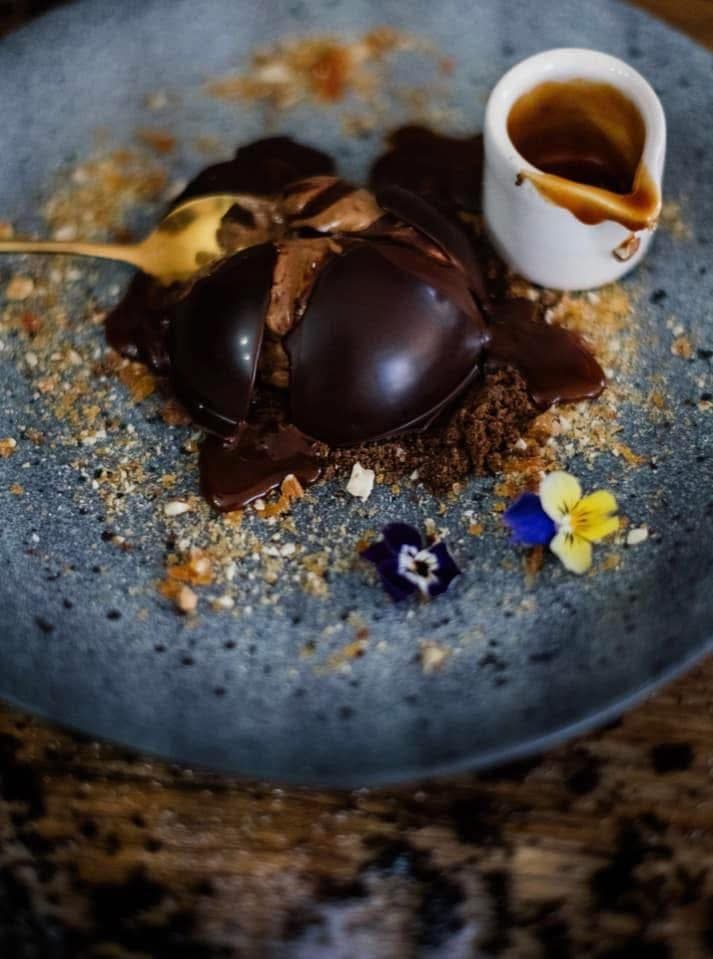 Glossy chocolate dome with caramel and edible flowers